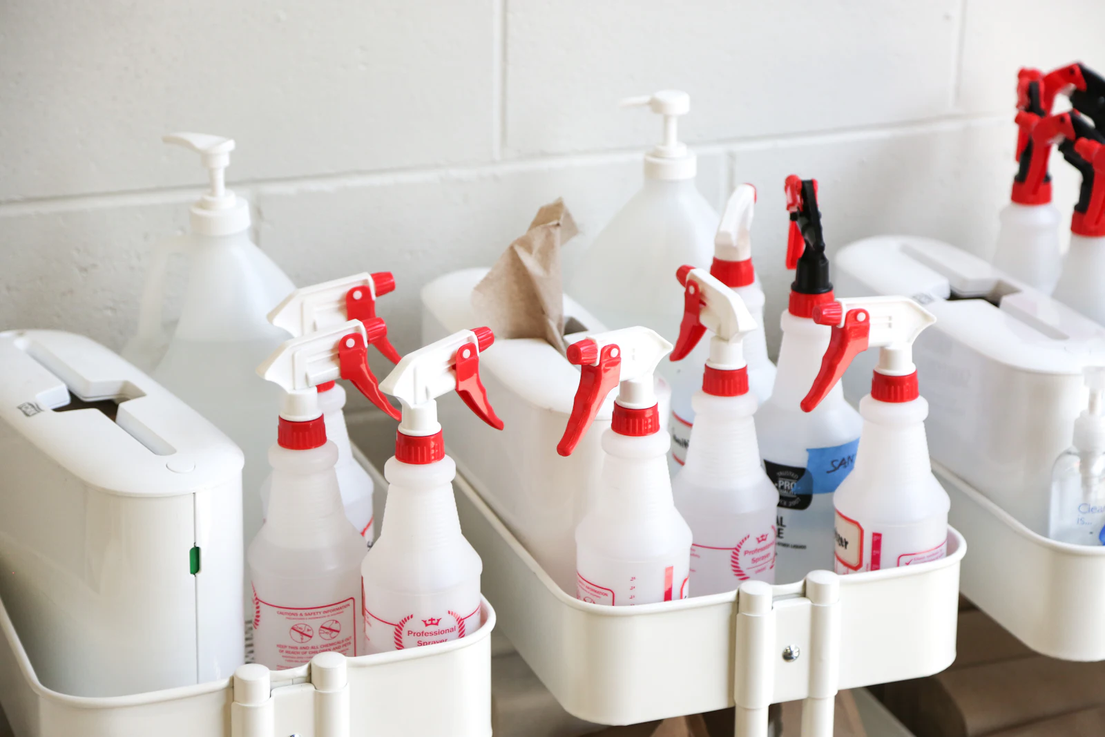 Trigger spray bottles and gallon jugs of cleaner in janitorial caddies