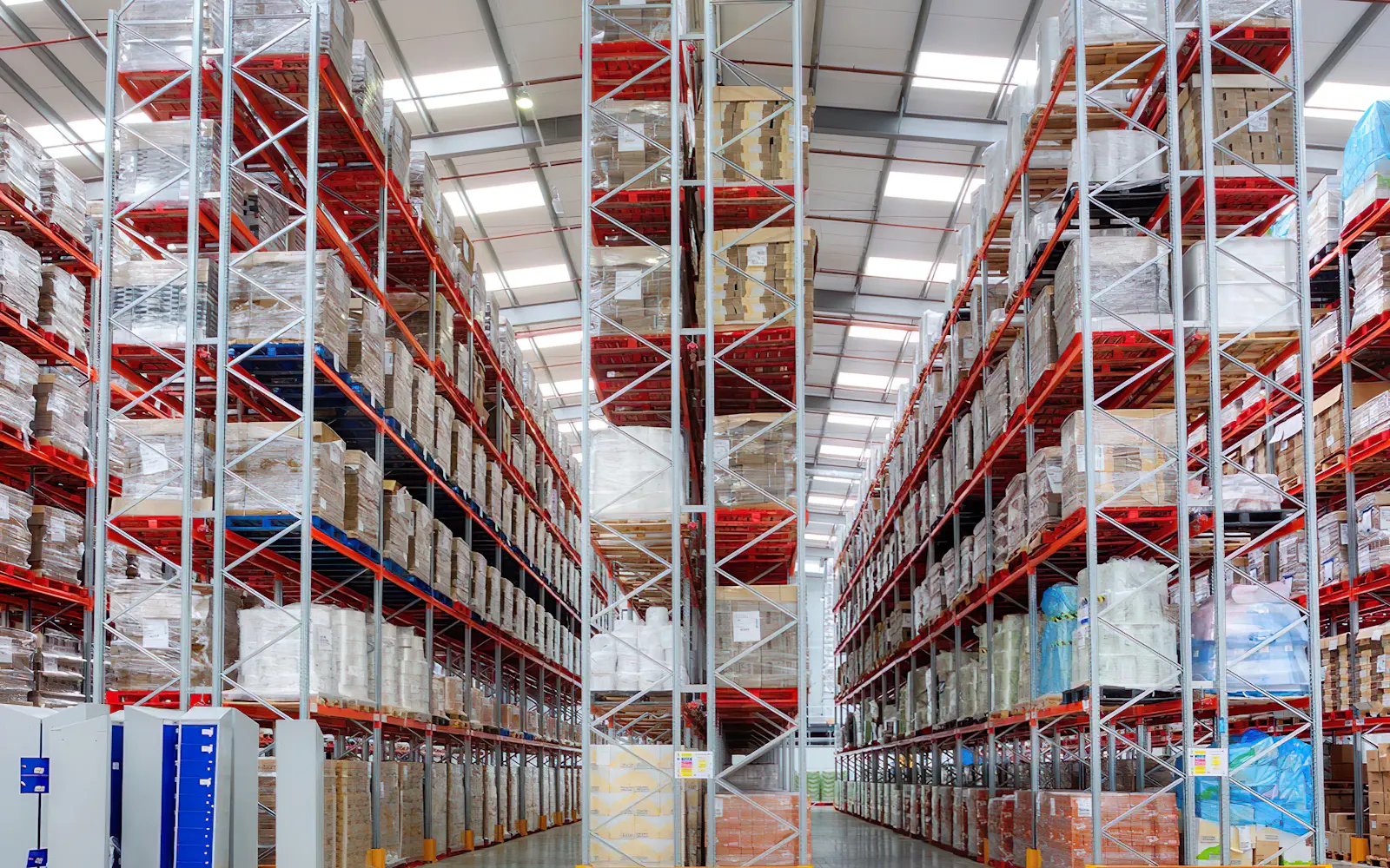 Tall red pallet racking holding stretch-wrapped pallets in a distribution warehouse