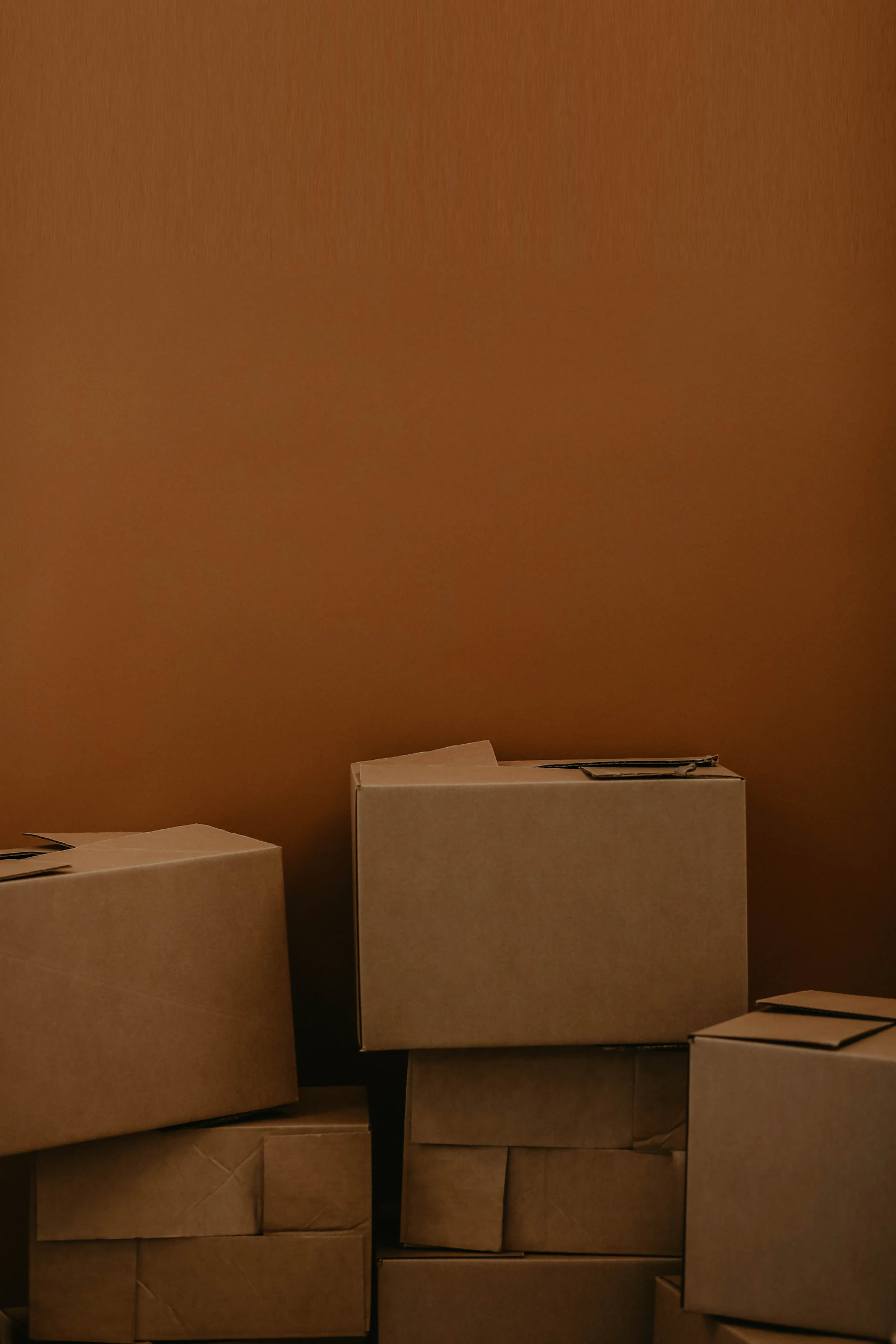 Plain corrugated boxes stacked against a brown wall