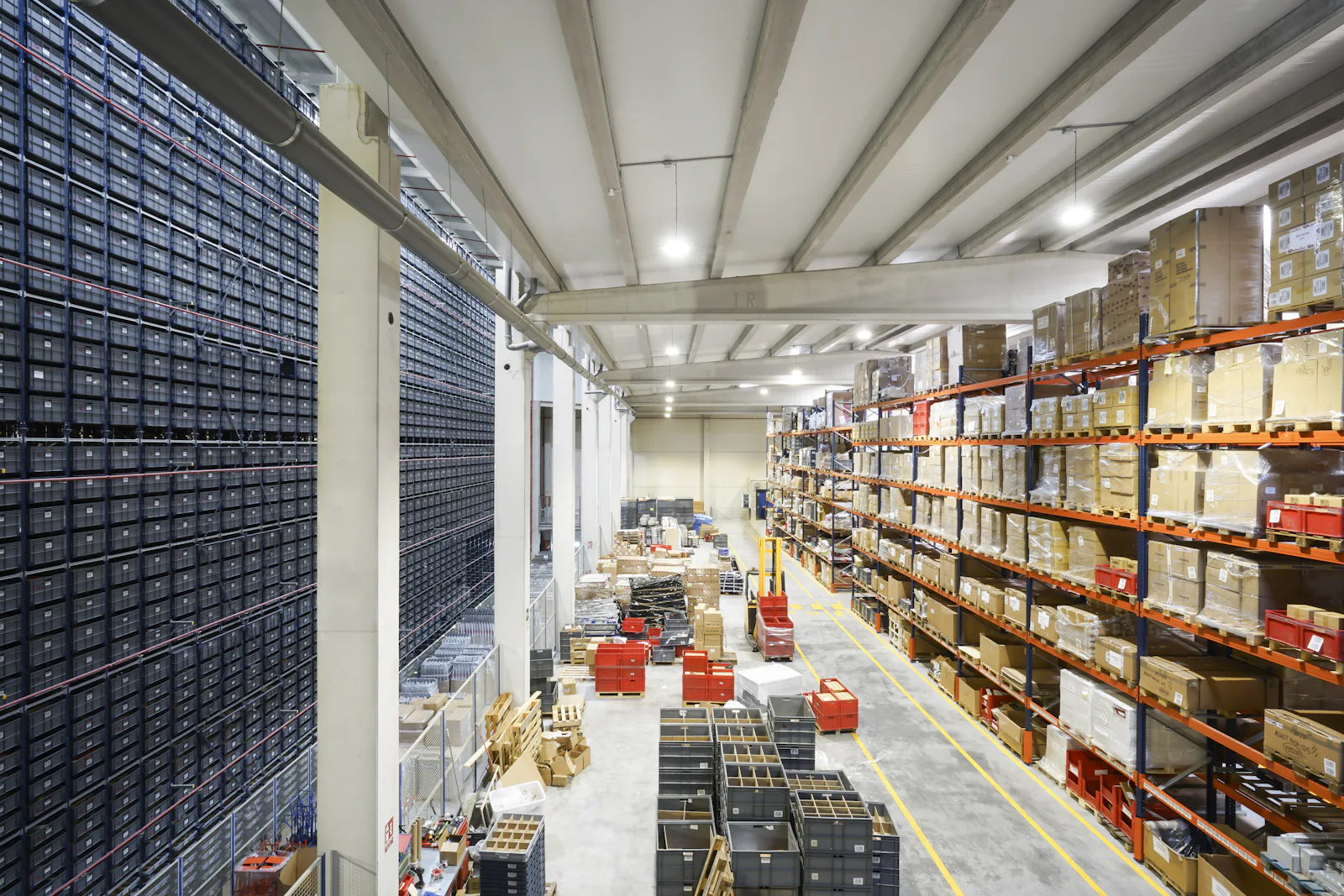 Overhead view of a warehouse floor with pallet racking, totes, and a picking area